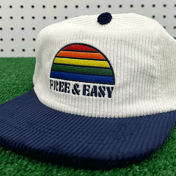 Rainbow Two Tone White and Navy Fat Corduroy Snapback Hat with rainbow embroidery and navy Free & Easy logo on a grass background - Free & Easy
