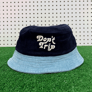 Free & Easy Don't Trip navy and blue corduroy bucket hat with white embroidered logo on grass background - Free & Easy