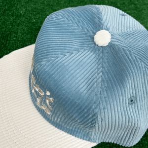 Don't Trip blue and white corduroy hat with white embroidered Don't Trip logo on grass background - Free & Easy