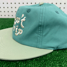 Load image into Gallery viewer, Don&#39;t Trip teal and mint lightweight hat with white embroidered Don&#39;t Trip logo on grass background - Free &amp; Easy
