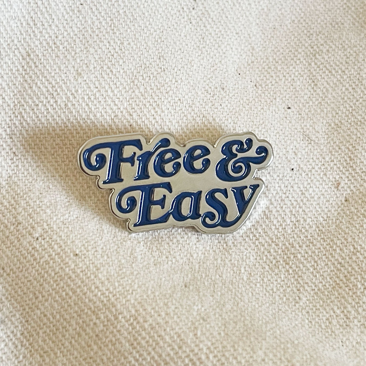 Free & Easy Enamel Pin in navy and silver on a natural background -Free & Easy
