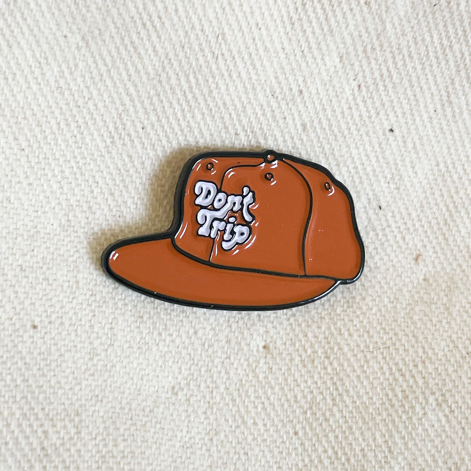 Don't Trip white and rust enamel pin hat on canvas background - Free & Easy