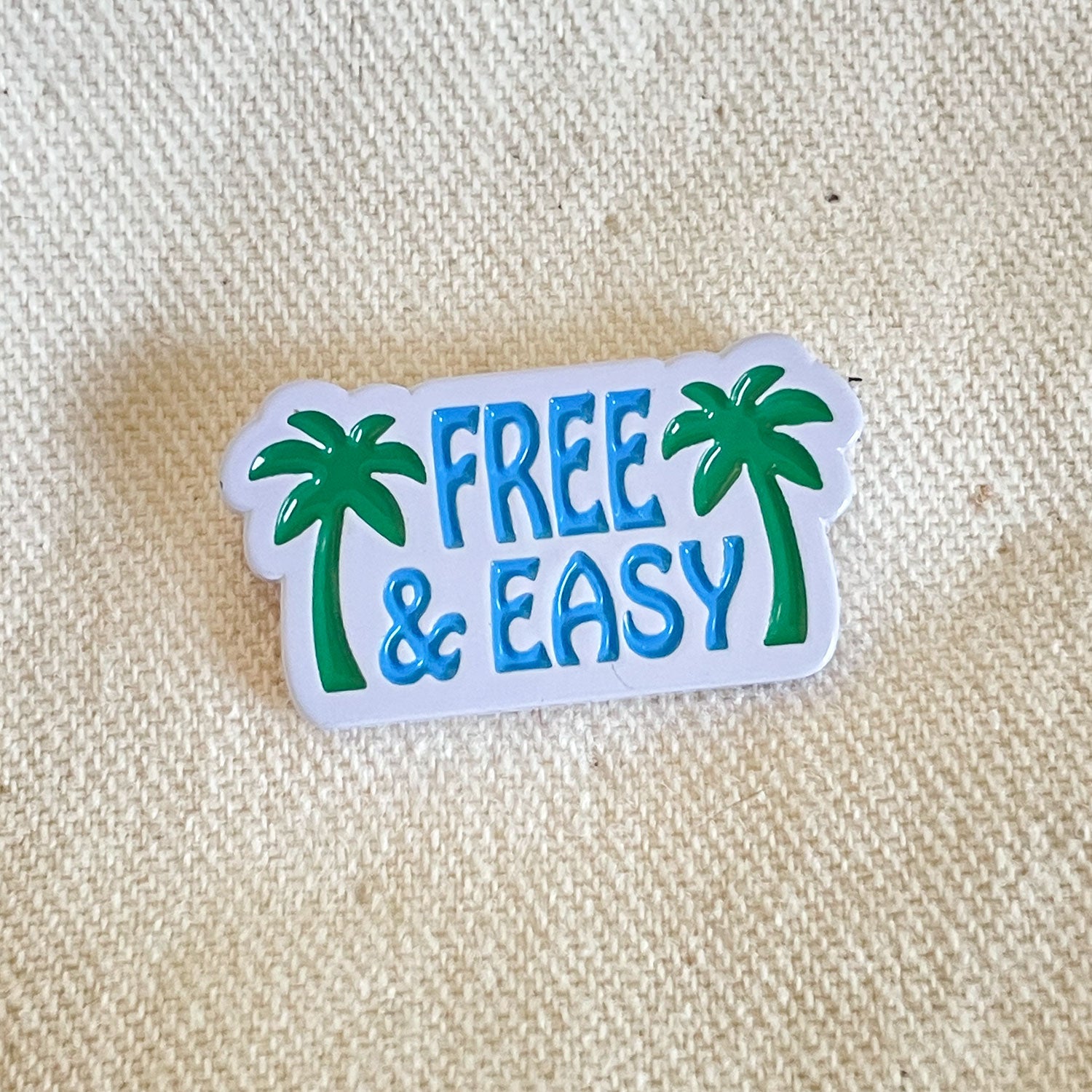 Palm Trees Enamel Pin in blue, green, and white on a white background -Free & Easy